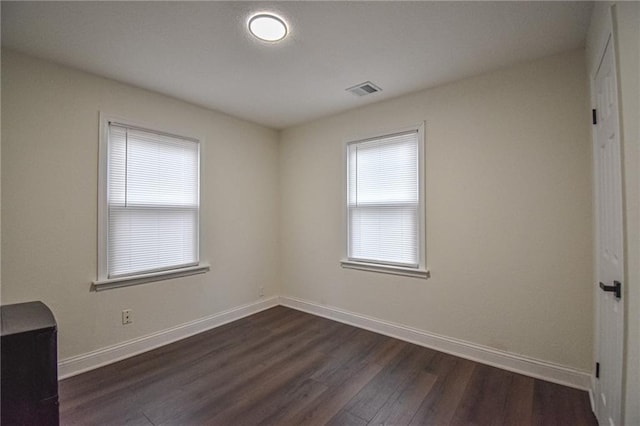 unfurnished room featuring visible vents, baseboards, and dark wood finished floors