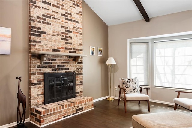 sitting room with baseboards, beam ceiling, a brick fireplace, and dark wood-style flooring