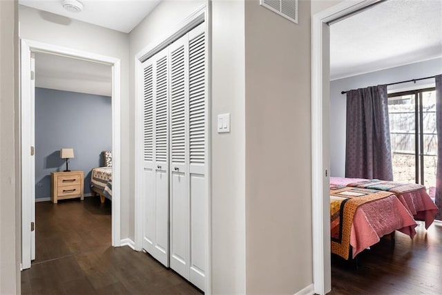 hallway with dark wood-style floors, visible vents, and baseboards