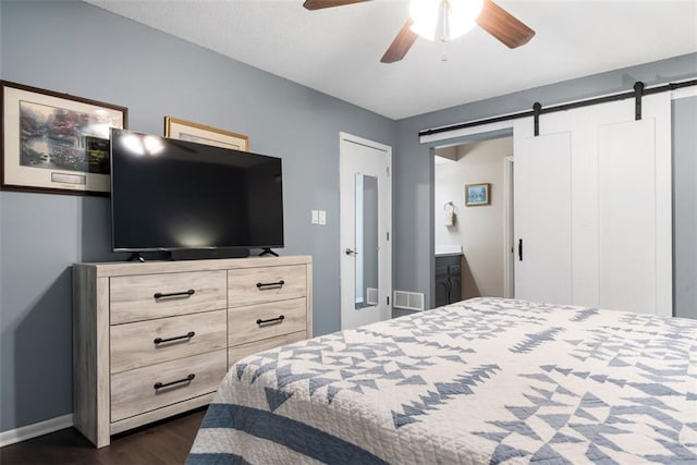 bedroom featuring baseboards, visible vents, dark wood finished floors, ceiling fan, and a barn door