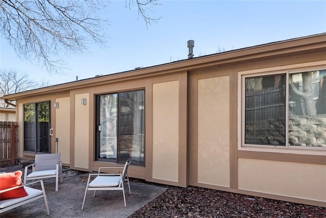 back of property with stucco siding, fence, and a patio area