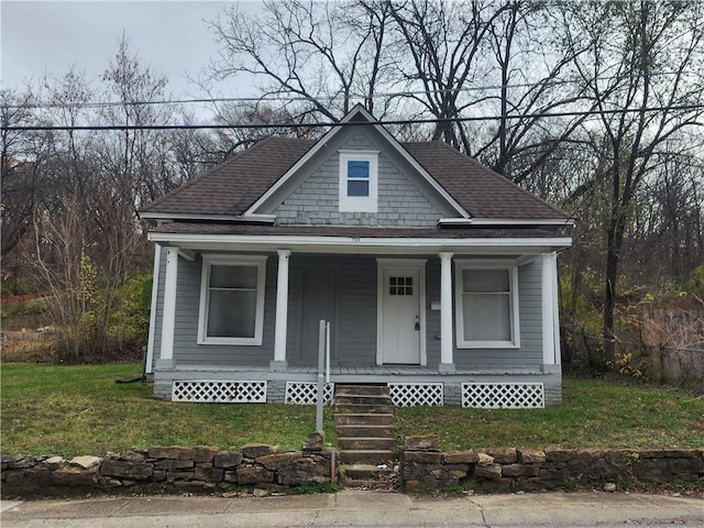 view of front of home with a porch, a shingled roof, and a front yard