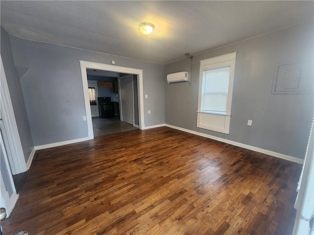 unfurnished room featuring dark wood-style floors, baseboards, and a wall unit AC