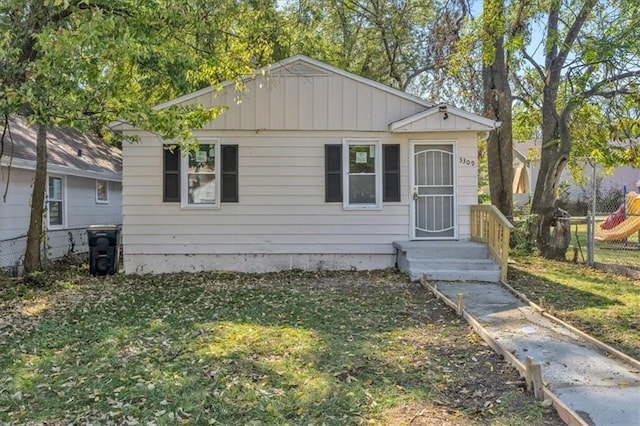 bungalow featuring a front lawn and fence