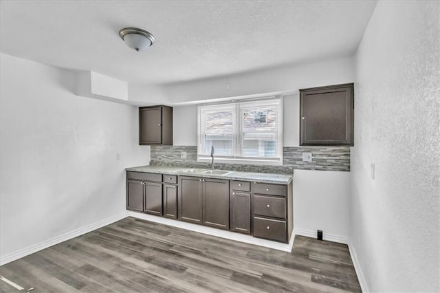 3309 E 69th St, Kansas City, MO 64132 - kitchen featuring a sink, dark wood-style floors, decorative backsplash, baseboards, and dark brown cabinets