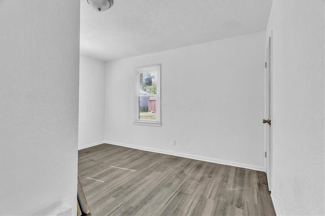 3309 E 69th St, Kansas City, MO 64132 - spare room with wood finished floors, baseboards, and a textured ceiling