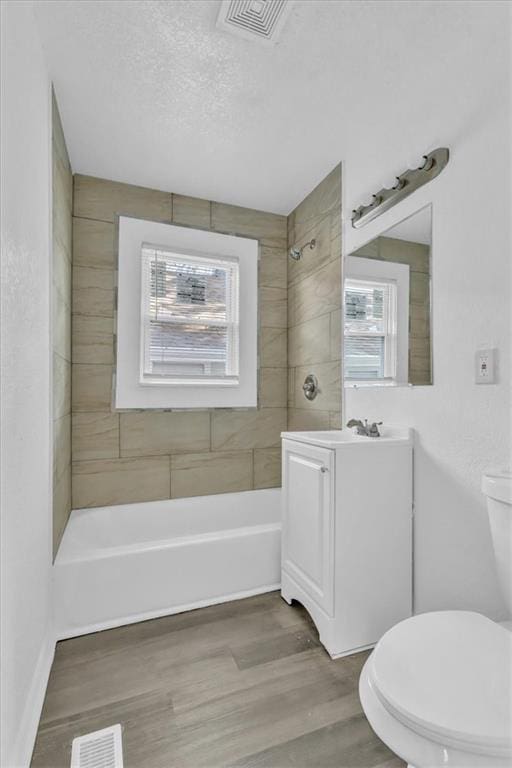 3309 E 69th St, Kansas City, MO 64132 - full bathroom with visible vents, toilet, a textured ceiling, shower / washtub combination, and wood finished floors