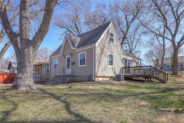 view of side of property featuring a wooden deck, a lawn, and a shingled roof