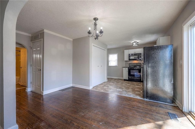 interior space with baseboards, arched walkways, a textured ceiling, and wood finished floors