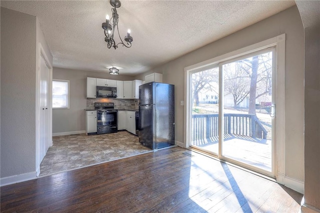 kitchen with black appliances, tasteful backsplash, an inviting chandelier, white cabinets, and light wood finished floors