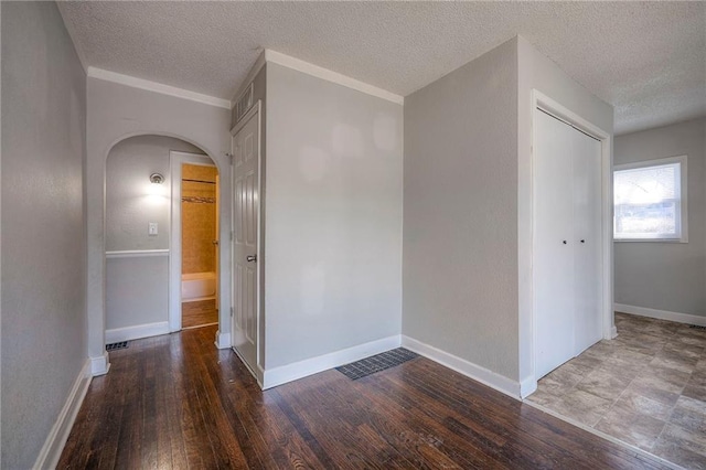 spare room featuring arched walkways, baseboards, and hardwood / wood-style floors