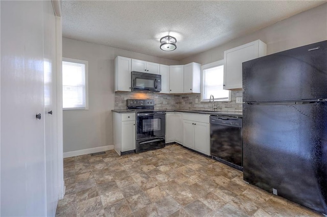 kitchen featuring baseboards, a sink, decorative backsplash, black appliances, and white cabinets