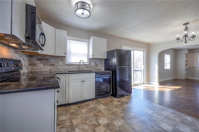 kitchen with dark countertops, tasteful backsplash, arched walkways, black appliances, and a sink