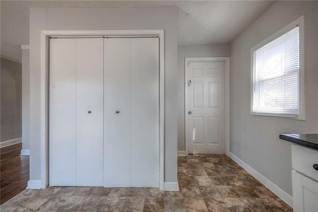 unfurnished bedroom featuring a closet, a textured ceiling, and baseboards