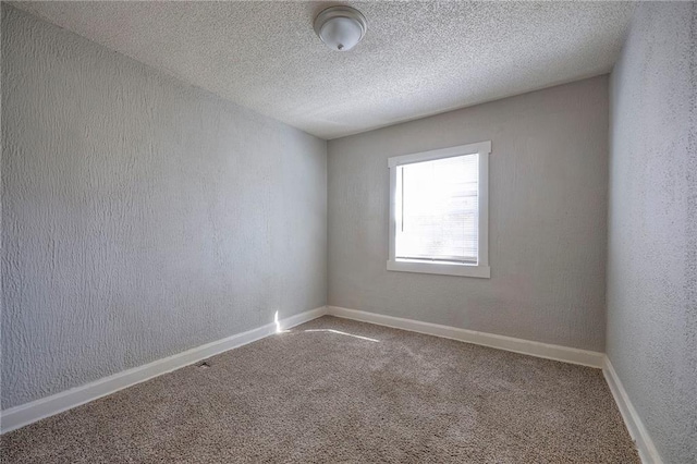 carpeted spare room with a textured ceiling, baseboards, and a textured wall