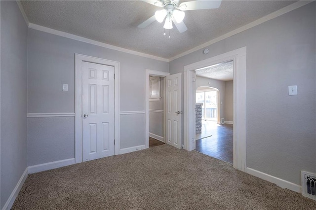 carpeted empty room featuring visible vents, a ceiling fan, a textured ceiling, crown molding, and baseboards