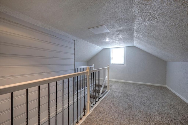 additional living space featuring lofted ceiling, carpet, baseboards, and a textured ceiling