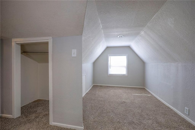 bonus room featuring vaulted ceiling, carpet, a textured wall, and a textured ceiling