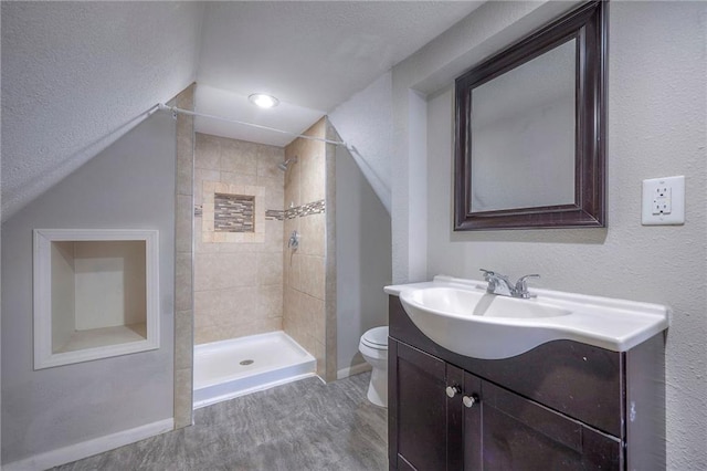 bathroom with baseboards, tiled shower, toilet, and vanity