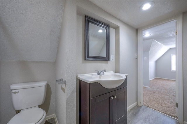 half bathroom with baseboards, toilet, vanity, a textured wall, and a textured ceiling