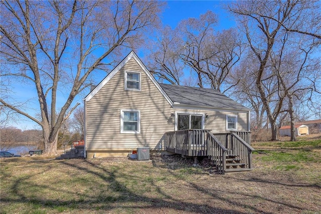 back of property with a deck, a yard, and central AC