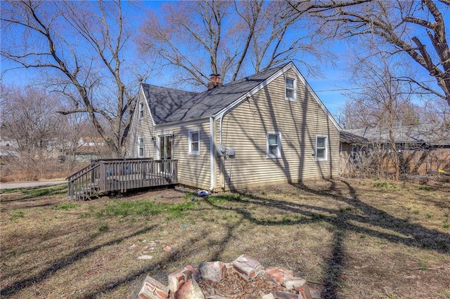 view of property exterior featuring a yard, a chimney, a shingled roof, and a deck