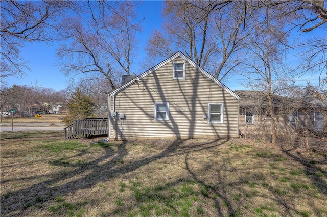 view of side of home with a deck and a lawn