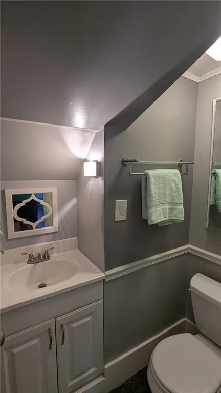 bathroom featuring toilet, vanity, and ornamental molding