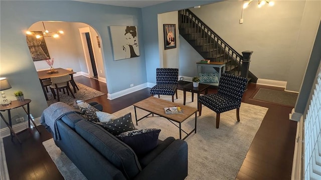 living area featuring baseboards, arched walkways, wood finished floors, and stairs