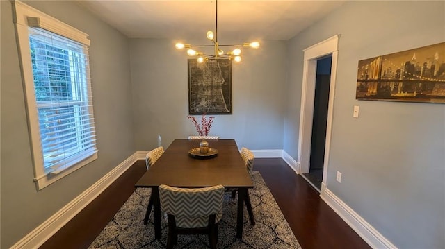 dining area featuring a notable chandelier, baseboards, and dark wood-style flooring