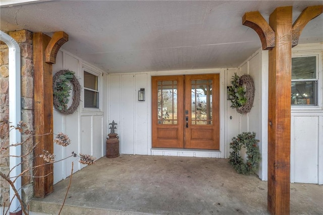 doorway to property with french doors, board and batten siding, and a porch