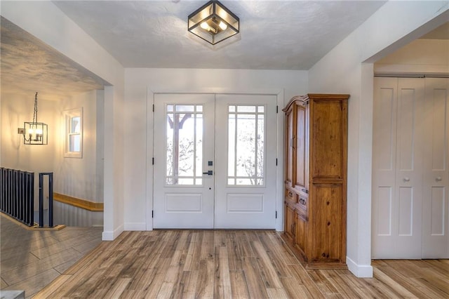 foyer entrance with french doors, baseboards, and wood finished floors