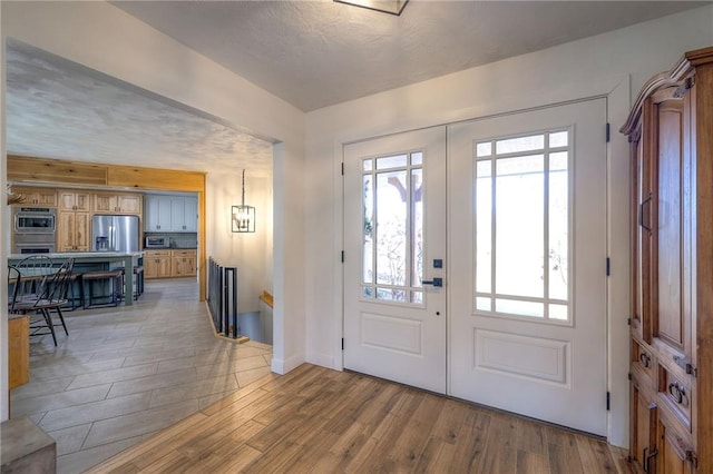 entrance foyer with light wood-type flooring, plenty of natural light, and french doors