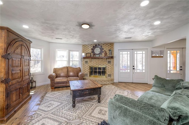 living area with visible vents, french doors, a textured ceiling, and hardwood / wood-style floors