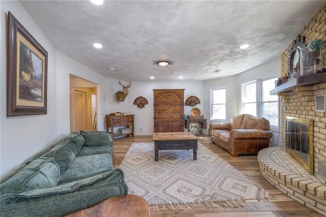 living room with wood finished floors, recessed lighting, a fireplace, and a textured ceiling