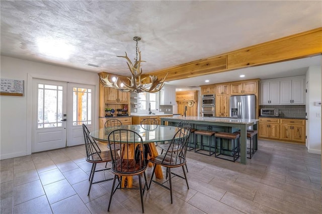 dining room with a toaster, french doors, baseboards, and a chandelier