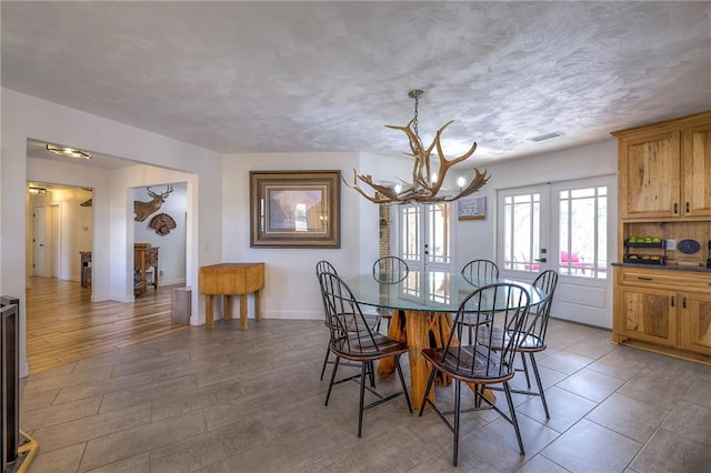 dining room featuring visible vents, a textured ceiling, wood finished floors, french doors, and baseboards