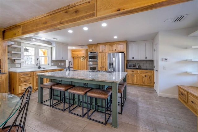 kitchen with visible vents, a sink, a spacious island, stainless steel appliances, and a breakfast bar area