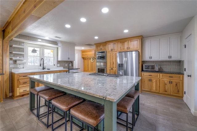 kitchen featuring backsplash, appliances with stainless steel finishes, a large island with sink, and a sink