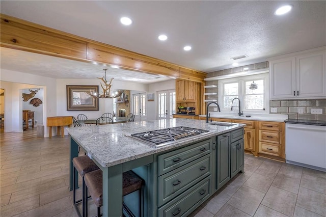 kitchen featuring dishwasher, stainless steel gas stovetop, plenty of natural light, and a breakfast bar area