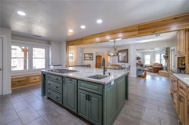 kitchen with an island with sink, a sink, open floor plan, recessed lighting, and stainless steel gas cooktop