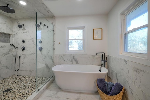 bathroom with a marble finish shower, a wainscoted wall, a freestanding bath, marble finish floor, and tile walls