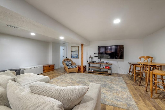 living room with recessed lighting, visible vents, and wood finished floors