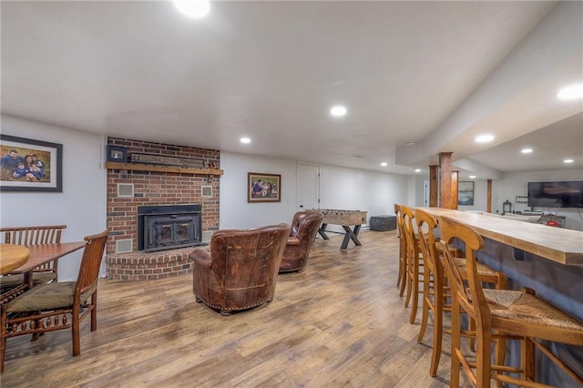 living area featuring a brick fireplace, recessed lighting, and wood finished floors