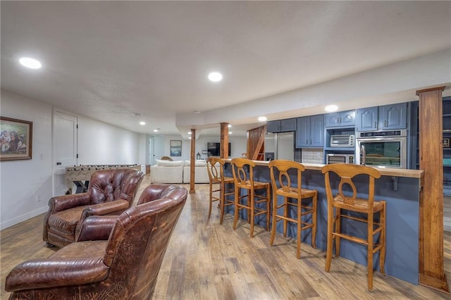 living area featuring recessed lighting, light wood-type flooring, and baseboards