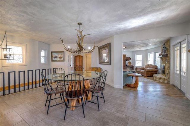 350 NW 71p Rd, Clinton, MO 64735 - dining room featuring a brick fireplace, a textured ceiling, baseboards, and a notable chandelier