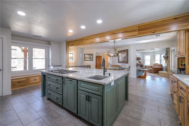 350 NW 71p Rd, Clinton, MO 64735 - kitchen with stainless steel gas cooktop, open floor plan, an island with sink, a textured ceiling, and a sink