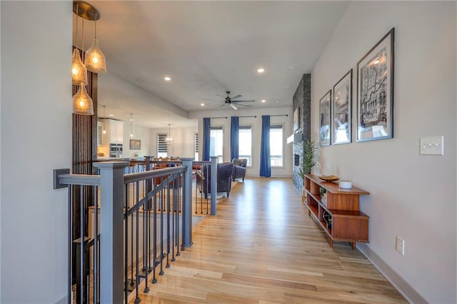 corridor featuring an upstairs landing, recessed lighting, and light wood-style floors