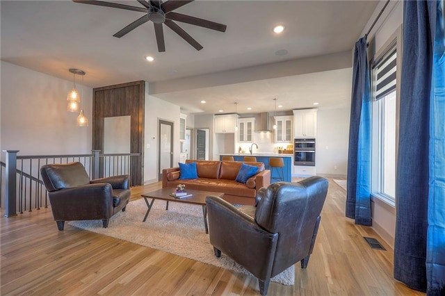 living room featuring recessed lighting, light wood-style flooring, visible vents, and ceiling fan