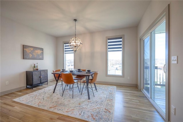 dining space with an inviting chandelier, light wood-style flooring, and baseboards